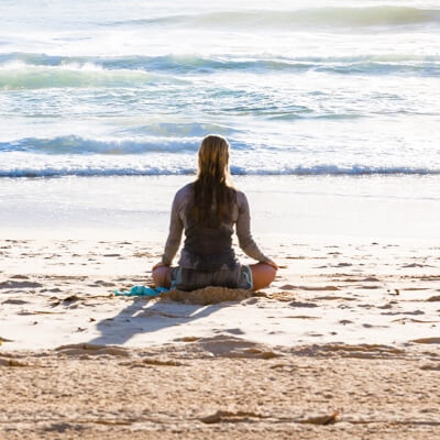 an woman meditating on a beach